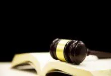 مطرقة قاضٍ على كتاب قانون مفتوح