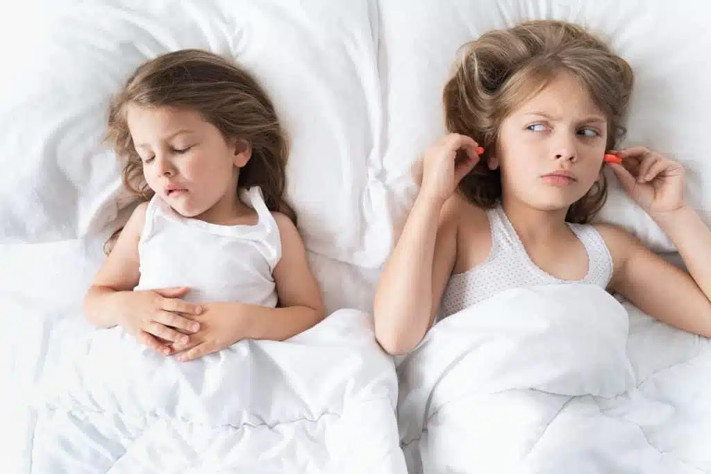 little girls sleep in bed. one is snoring hard, sister is plugging her ears with earplugs.early morning wake up,rise to kindergarten, school. bedtime,sweet dreams.kids correct daily routine for child